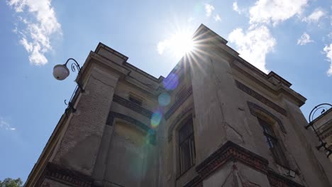 a-shot-of-an-old-building-with-windows-and-street-lamp-where-the-rays-of-the-sun-peek-out-on-the-roof