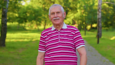 Happy-lovely-senior-old-gray-haired-grandfather-in-casual-red-t-shirt-on-summer-park-background