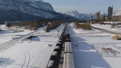 Vista-Aérea-De-Un-Tren-De-Carga-Pasando-Por-Un-Paisaje-Cubierto-De-Nieve-Cerca-De-La-Planta-De-Cemento-Lafarge-Exshaw