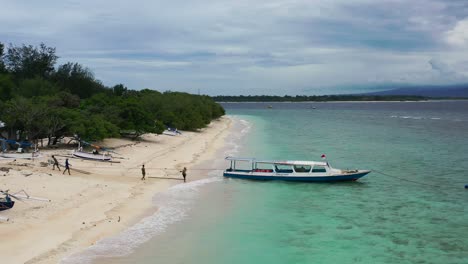 locals-anchoring-a-fishing-boat-on-a-tropical-white-sand-beach-island-at-Gili-Trawangan,-aerial