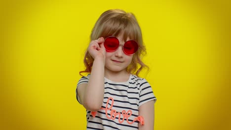 Happy-playful-kid-girl-in-sunglasses-blinking-eye,-looking-at-camera-with-smile,-winking,-flirting