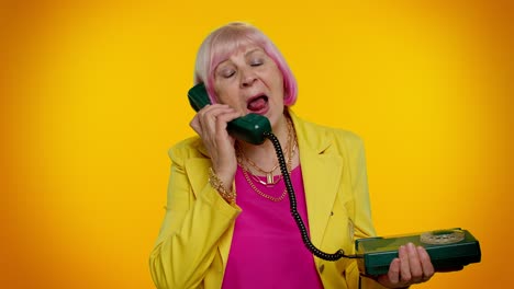 Crazy-elderly-granny-old-woman-talking-on-wired-vintage-telephone-of-80s,-fooling-making-silly-faces