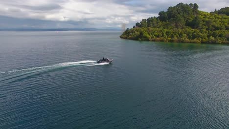 Aerial-shot-following-a-fishing-boat-navigating-on-a-lake-at-golden-hour