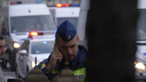 Polizist-Erhält-Befehl-Per-Telefon,-Polizeitransporter-Im-Hintergrund