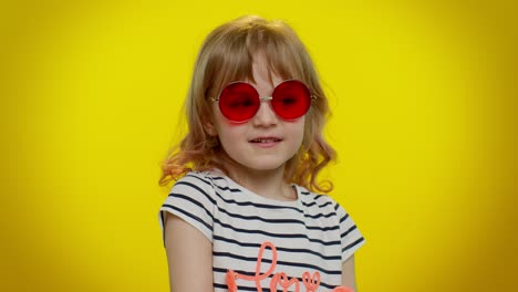 Playful-happy-kid-girl-in-sunglasses-blinking-eye,-looking-at-camera-with-smile,-winking,-flirting