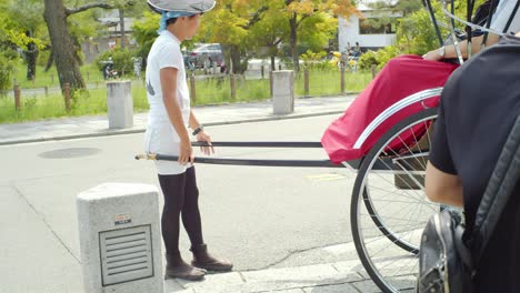 Man-pulling-tourists-in-a-rickshaw-on-a-bridge-in-Kyoto,-Japan-soft-lighting-slow-motion-4K