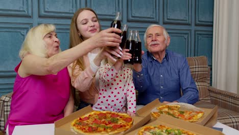 Happy-multigenerational-family-having-lunch-party-at-home,-eating-pizza-food,-raising-toast-together