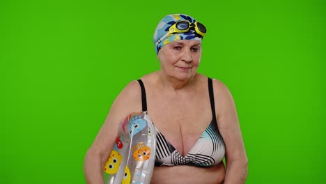 Elderly-woman-tourist-in-swimsuit-bra,-swim-goggles-with-swimming-ring,-looking-around-on-chroma-key