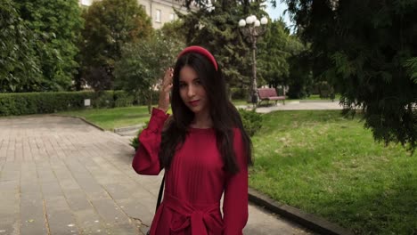 Graceful-positive-girl-in-red-touches-hair-in-the-city