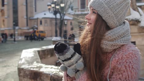 Girl-tourist-with-hot-drink-in-cup-looking-around-through-street-in-town-during-holiday-vacations