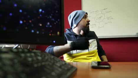 Profile-of-funky-confident-young-man-with-hat-and-black-gloves-discussing-with-a-flip-chart-in-background-to-colleagues-in-boardroom,-dolling-zoom-view