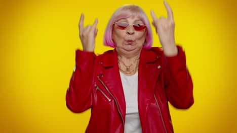 Overjoyed-delighted-crazy-elderly-woman-showing-rock-n-roll-gesture-by-hands,-cool-sign,-dancing