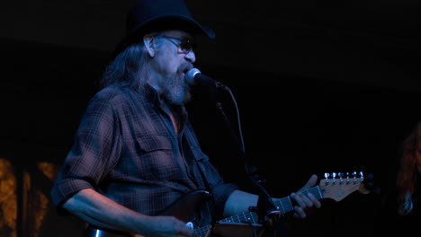 Male-country-singer-performs-with-guitar-at-night-festival,-medium-shot