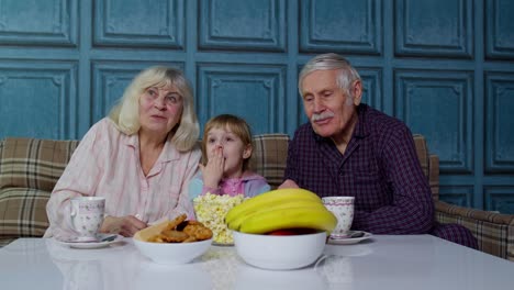 Senior-grandfather-and-grandmother-happy-laughing,-eating-popcorn,-watching-cartoons-movies-at-home