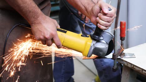 yellow-powertool-cutting-metal-creating-strong-red-sparks-that-bounce-on-the-worker-clothe