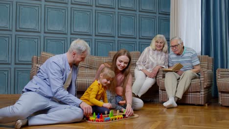 Happy-family-leisure-at-home-child-daughter-playing-with-mother-and-father-railway-toy-game-on-floor