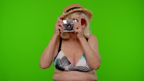 Mature-woman-photographer-traveler-in-sunglasses-taking-picture-photos-on-retro-camera,-chroma-key