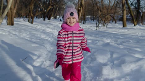 Smiling-child-kid-running,-having-fun,-dancing,-fooling-around-on-snowy-road-in-winter-park-forest