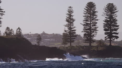 Waves-break-onto-the-rocky-shoreline-of-a-small-coastal-town