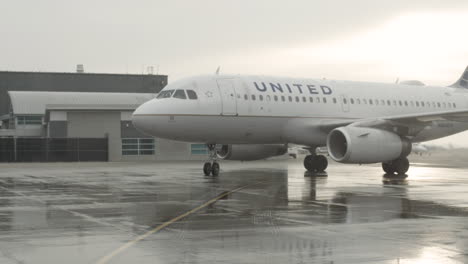 Aircraft-flight-arrival-at-gate-pulling-in-on-wet-tarmac-in-bad-weather