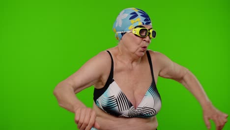 Mature-woman-traveler-swimmer-in-swim-goggles,-dancing,-showing-swimming-movements,-chroma-key