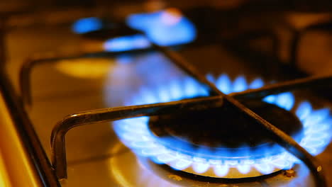 Close-up-of-a-gas-burner-igniting-which-turns-on-in-sequence-with-blue-flames-on-a-stove