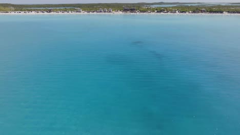 Aerial-view-over-a-ferry-full-of-people-moving-towards-the-Half-Moon-beach,-in-sunny-Bahamas