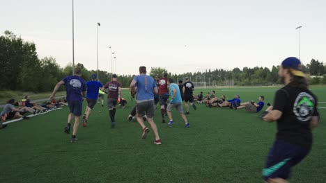 Many-men-doing-exercise-and-recreational-activities-on-a-soccer-field-in-the-early-morning