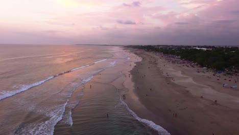 Aerial-drone-shot-of-surfers-surfing-at-Canggu-beach-during-the-sunset,-Bali,-Indonesia