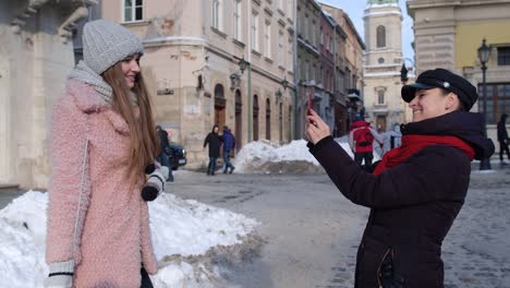 Sisters-couple-bloggers-taking-photo-pictures,-posing,-making-online-video-vlog-on-mobile-phone