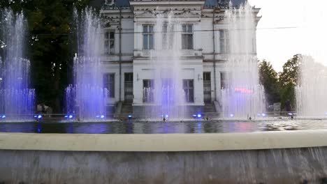 Toma-Panorámica-De-Fuentes-Coloridas-Con-Una-Galería-De-Arte-Al-Fondo-En-Pitesti,-Rumania