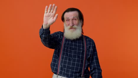 Happy-friendly-elderly-man-waves-hand-palm-in-hello-gesture-welcomes-someone-positive-emotions