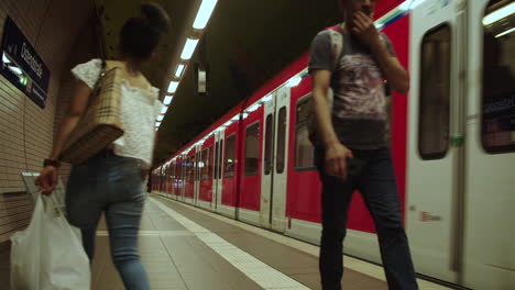 Frankfurt-metro-station,-red-train-arrives-with-passengers-waiting,-static