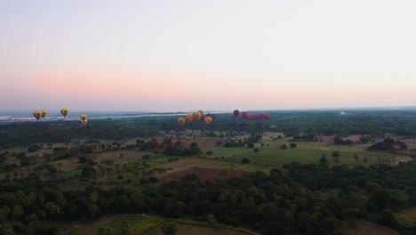 Aerial-slide-left-of-hot-air-balloons-lifting-off-at-dawn-in-Bagan,-Myanmar