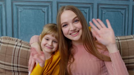 Child-kid-daughter-with-mother,-embracing,-waving-hands-to-camera-doing-hello-welcome-or-bye-gesture