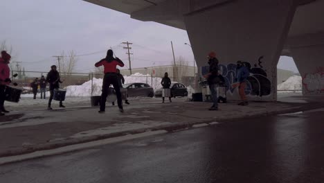 Drummers-dance-and-play-under-highway-bridge-in-snowy-Montreal-during-winter