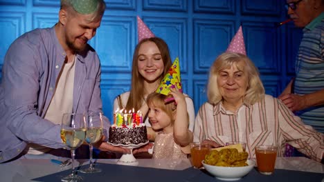 Girl-kid-blowing-candles-on-cake-making-wish,-having-fun,-celebrating-birthday-party-with-family