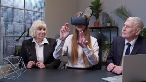 Woman-wearing-virtual-reality-glasses-tries-3D-app-for-VR-helmet-while-colleagues-supporting-her