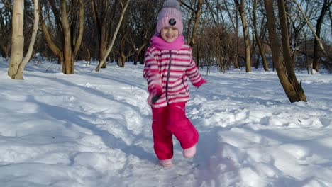 Smiling-child-kid-running,-having-fun,-dancing,-fooling-around-on-snowy-road-in-winter-park-forest