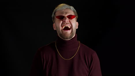 Stylish-smiling-young-man-in-red-sunglasses-looking-at-camera,-laughting-at-loud,-feeling-happiness