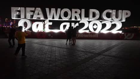 Touristen,-Die-Nachts-Fotos-Machen-Und-Vor-Dem-Logo-Der-FIFA-Weltmeisterschaft-2022-Posieren