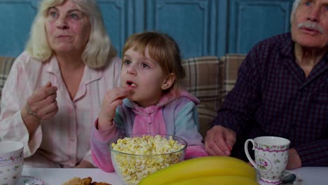 Senior-grandfather-and-grandmother-eating-popcorn-and-getting-scared-watching-horror-movies-at-home