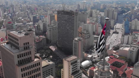 Aerial-view-of-Altino-Arantes-building,-called-Banespao-with-the-flag-fluttering,-Sao-Paulo-downtown,-Brazil