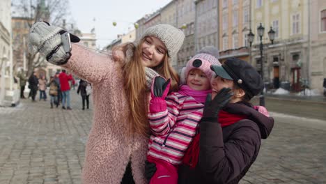 Women-tourists-taking-selfie-photos-on-mobile-phone-with-adoption-child-girl-on-winter-city-street