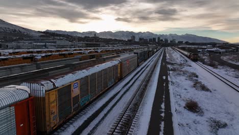 Increíble-Toma-Aérea-Paralela-De-Un-Tren-En-Movimiento-En-El-Norte-De-Salt-Lake,-Utah,-Al-Amanecer-En-Invierno