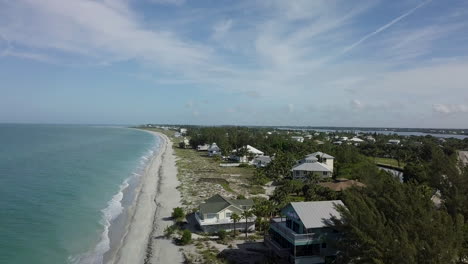 Drone-booms-down,-high-to-low,-with-view-of-private-beach-while-waves-rolling-onto-shore