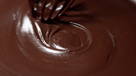 Chef-stirring-mixing-melted-liquid-premium-dark-chocolate-with-whisk-preparation-of-handmade-candies