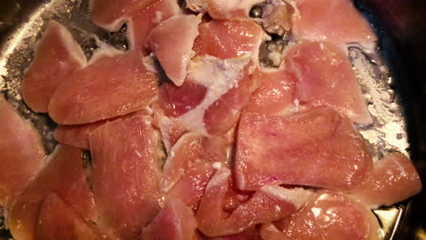 Raw-chicken-breast-meat-cooking-in-a-frying-pan