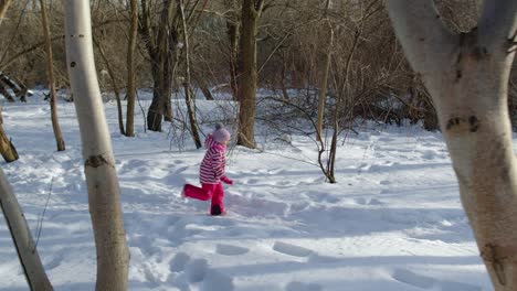 Fröhliches-Kleines-Mädchen,-Das-Auf-Einer-Verschneiten-Straße-Durch-Den-Winterparkwald-Im-Freien-Rennt