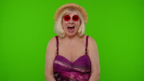 Amazed-senior-pensioner-woman-tourist-in-swimsuit-shocked-by-sudden-victory-saying-wow-on-chroma-key